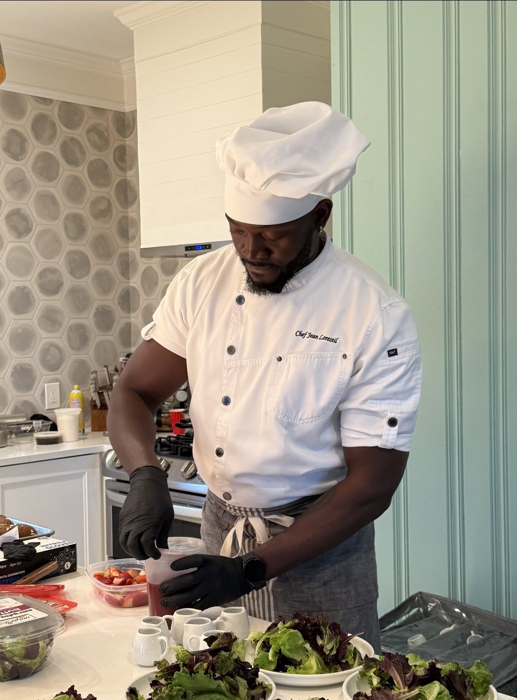 Chef Jean Lorestil plating dishes in a client's kitchen