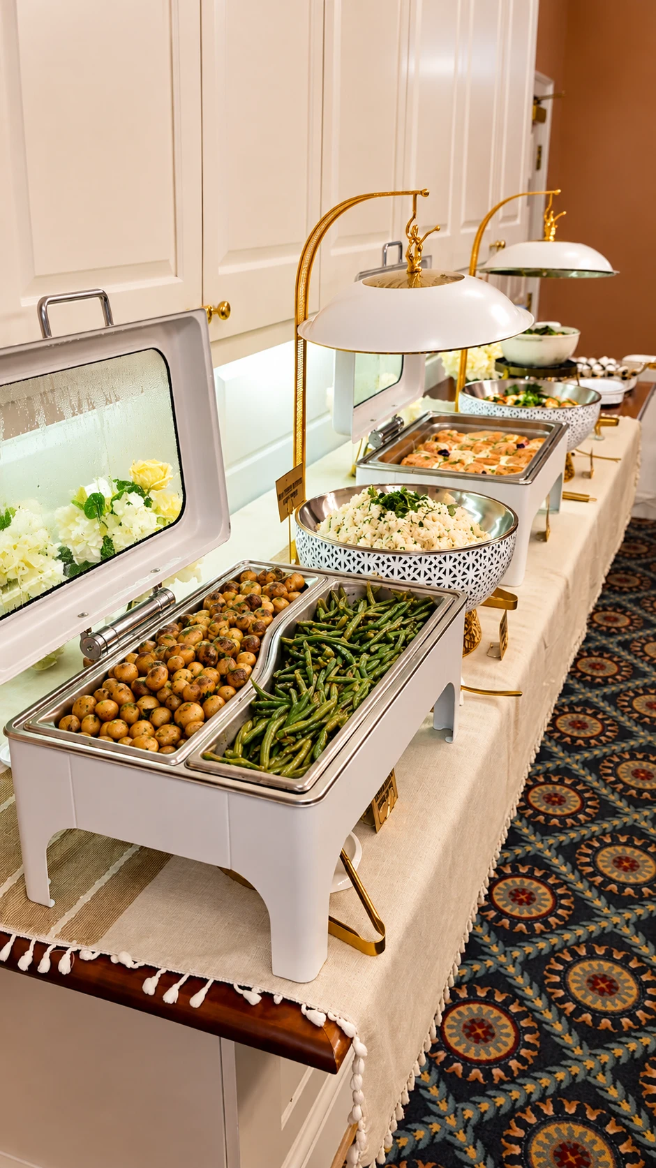 white and gold buffet presentation with vegetables, rice and warm dishes